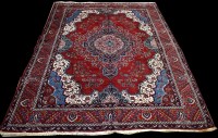 Lot 956 - A Heriz carpet, red ground decorated with...
