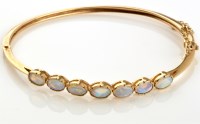 Lot 830 - An opal and 9ct. yellow gold bangle, the seven...