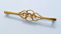 Lot 870 - A diamond set 18ct. yellow bar brooch, the...
