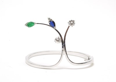 Lot 63 - A diamond, sapphire and emerald set bangle.