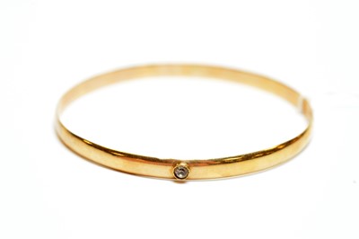 Lot 141 - Yellow metal bangle bezel set with a single white stone.