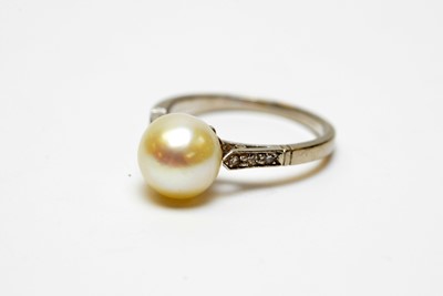 Lot 23 - A high-carat white metal, diamond, and pearl solitaire cocktail ring.