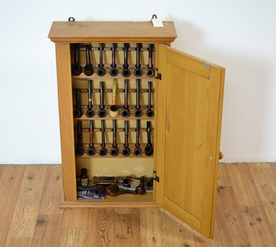 Lot 424 - A collection of tobacco pipes contained in a pine wall mounting cabinet