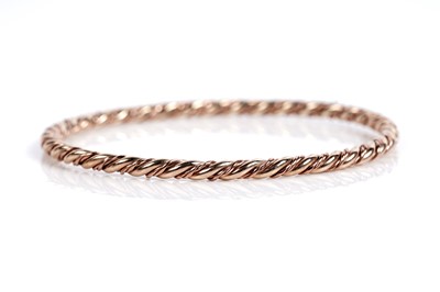 Lot 630 - A 9ct rose and yellow gold twist pattern bangle
