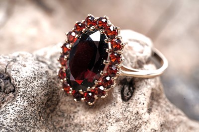 Lot 77 - A modern garnet flowerhead pattern dress ring