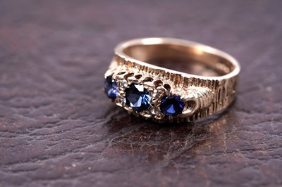 Lot 270 - A 1970's three-stone sapphire ring with bark-effect shank
