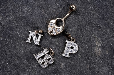 Lot 222 - A 9ct gold and CZ belly button bar; and three yellow metal and CZ pendants