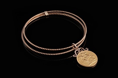 Lot 289 - A George VII gold sovereign suspended on a triple annuli bangle