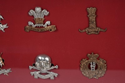 Lot 184 - A display of British regimental cap badges, mainly Dragoons, Lancers and Hussars