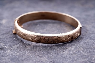 Lot 93 - A modern 9ct gold hinged bangle with foliate decoration