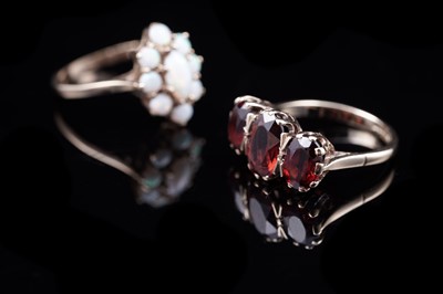 Lot 51 - A three stone garnet dress ring; and an opal flowerhead pattern ring