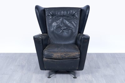 Lot 64 - A 1950’s black leather wingback revolving armchair