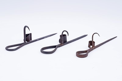 Lot 207 - Two 19th Century wrought iron ‘Sticking Tommy’ candle holders; and another