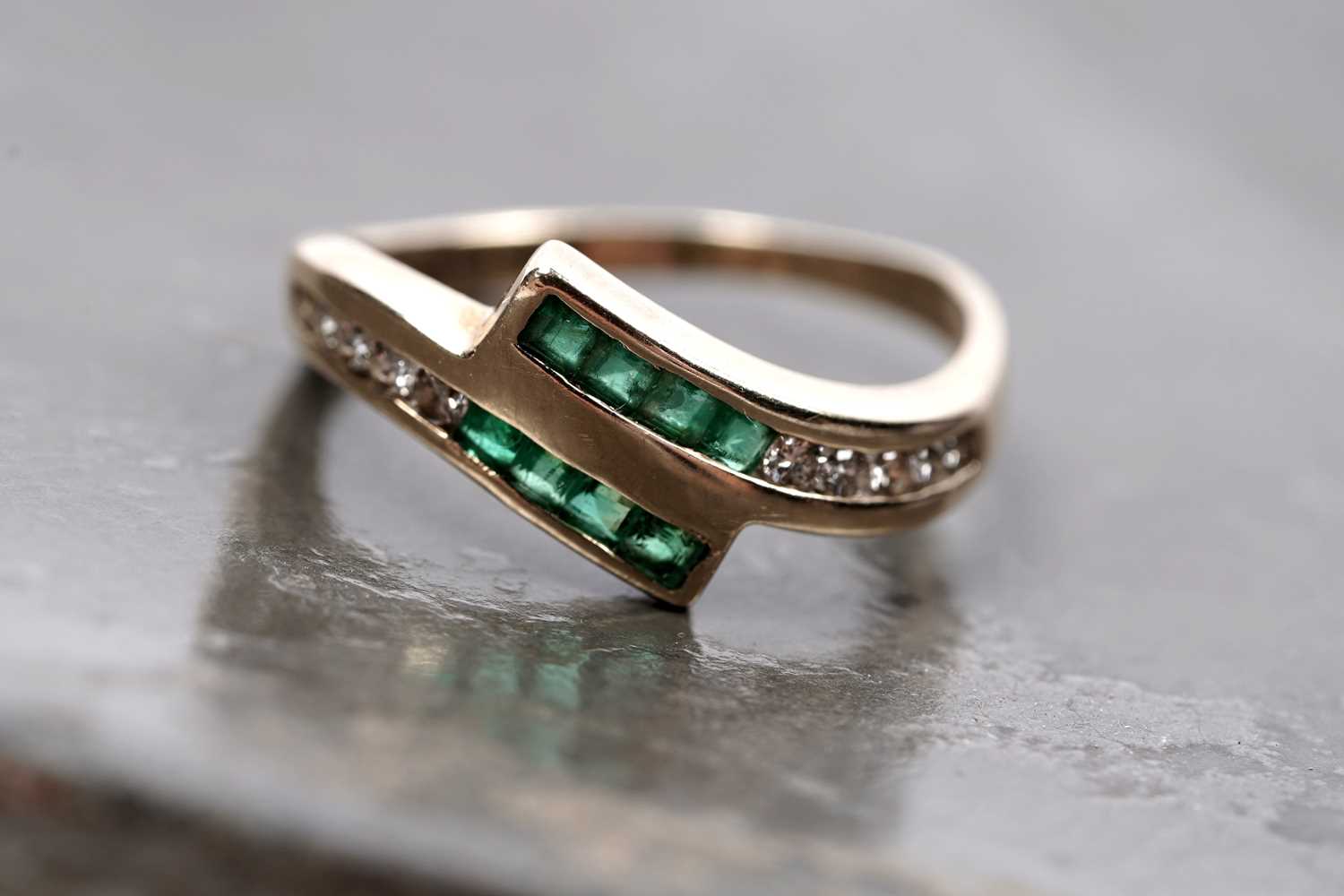 Lot 60 - A modern emerald and diamond cross-over ring