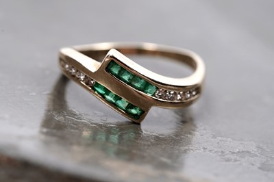 Lot 60 - A modern emerald and diamond cross-over ring