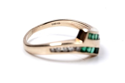 Lot 60 - A modern emerald and diamond cross-over ring