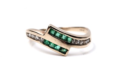 Lot 60 - A modern emerald and diamond cross-over ring