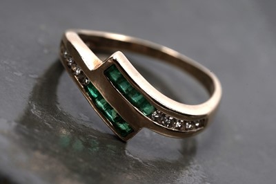 Lot 60 - A modern emerald and diamond cross-over ring