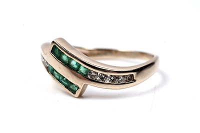 Lot 60 - A modern emerald and diamond cross-over ring