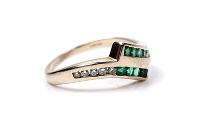 Lot 60 - A modern emerald and diamond cross-over ring