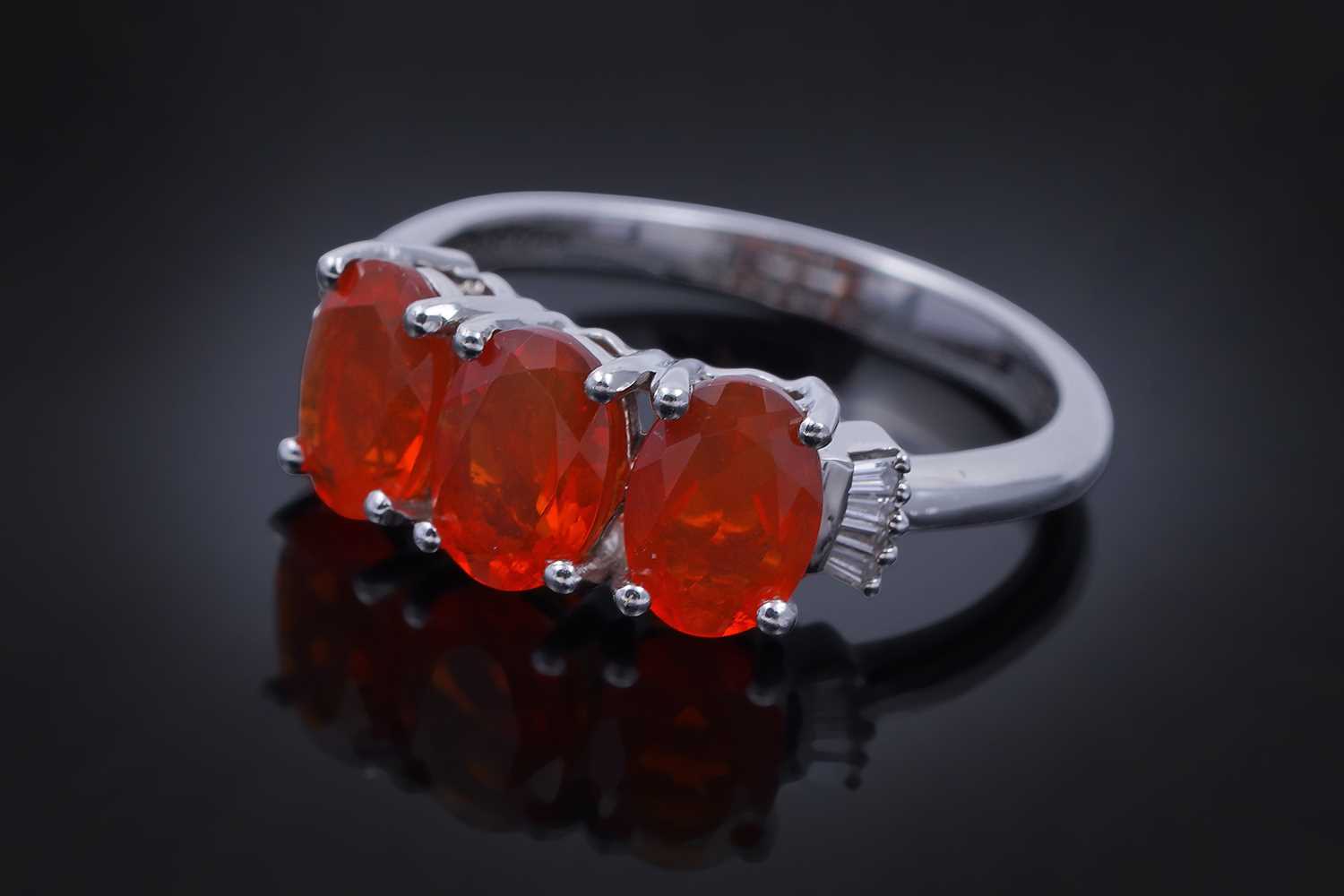 Lot 30 - A contemporary Rhapsody three-stone fire opal and diamond ring