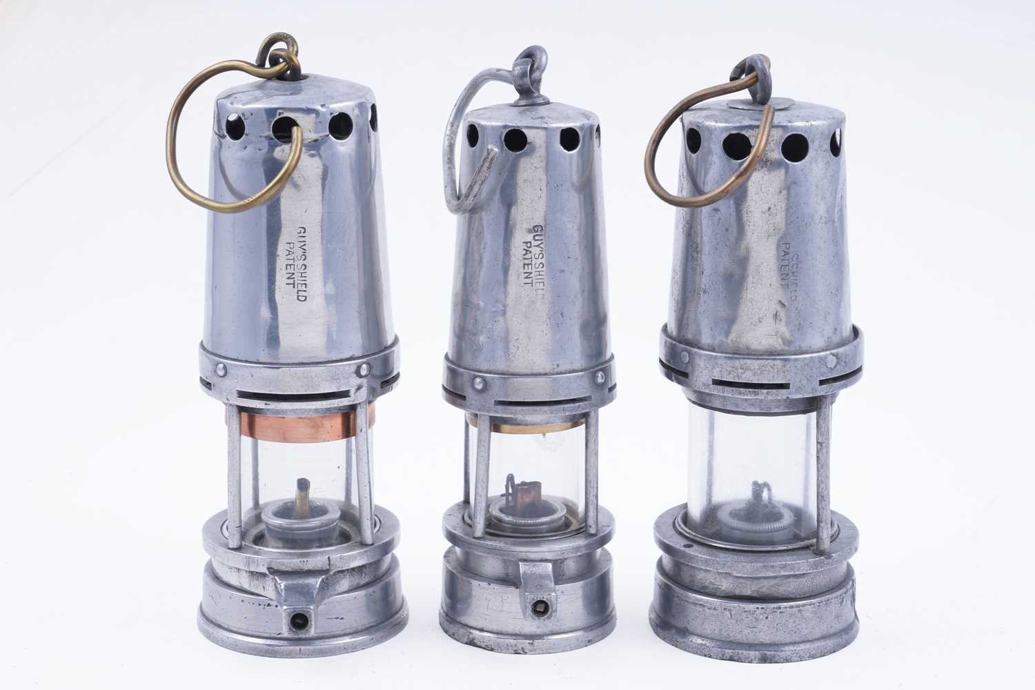 Lot 178 - Three aluminium-bodied ‘Guys Shield Patent’ lamps