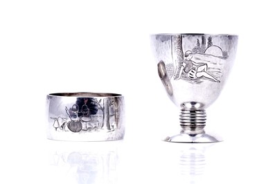 Lot 138 - A 1930s Art Deco silver egg cup and napkin ring set, engraved with scenes from fairytales